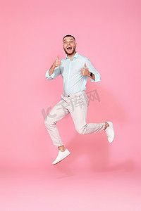 穿着夏天衣服的男人在粉红色的背景上跳跃。