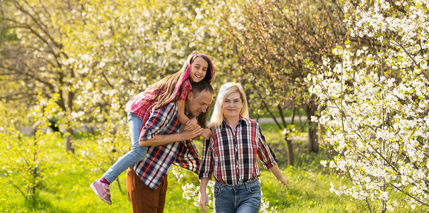 快乐的年轻家庭在绿色大自然中共度户外时光