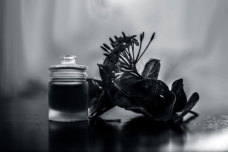 章五角星摄影照片_木质表面上红色五角花或埃及星花或茉莉花的特写，其提取的精油装在透明瓶中。