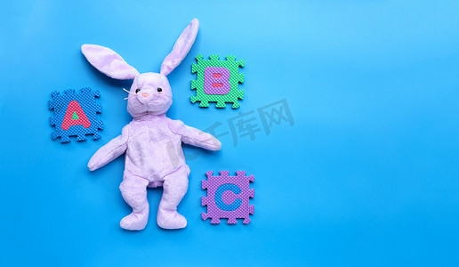 蓝色背景上有英文字母拼图的兔子玩具。