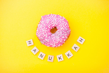 黄色背景上的粉色美味甜甜圈和木块上的铭文光明节快乐