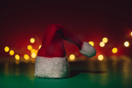 圣诞节绿色帽子摄影照片_等距绿色红色背景上的圣诞老人帽子。