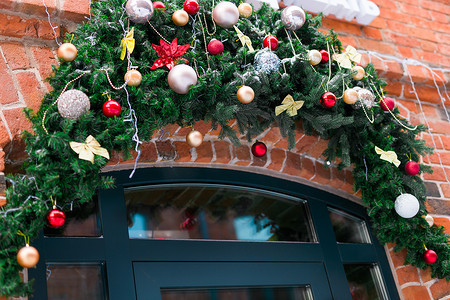时尚的圣诞冷杉树枝，在假日市场或城市街道的餐厅的门前挂着小玩意和闪闪发光的花环。