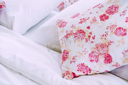 花卉图案摄影照片_明亮的卧室内饰，床上配有花卉图案枕头