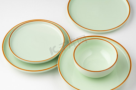 淡绿色卷轴摄影照片_一套带有橙色轮廓的淡绿色陶瓷餐具