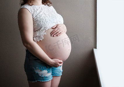 手捂肚子摄影照片_怀孕女孩的手捂着肚子，等待孩子的出生