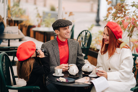 父亲三口摄影照片_一家时尚的三口之家正坐在咖啡馆外面的桌子旁喝咖啡。