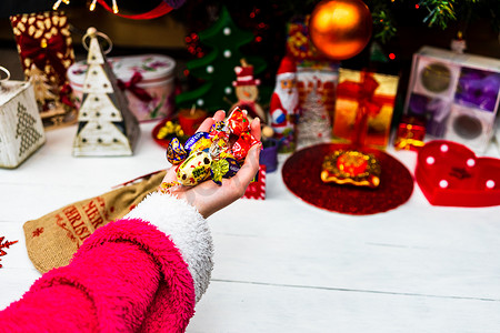手拿着巧克力糖在圣诞树前。 