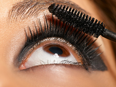 黑色眼影摄影照片_在时装秀上用睫毛膏刷睫毛和黑色眼影的女性的美容、化妆和眼睛。