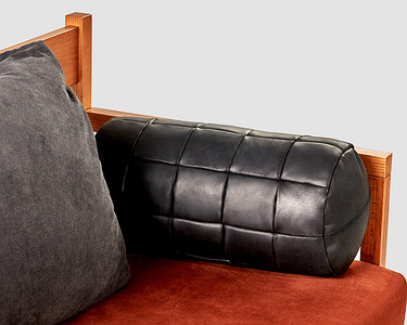 恐龙抱枕摄影照片_柔软的沙发上手工缝制的黑色皮革抱枕