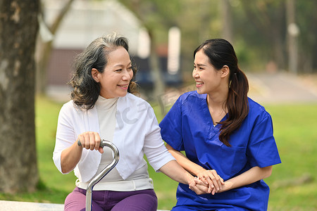 身着制服的积极女护士与家庭护理花园里的高级妇女进行愉快的交谈