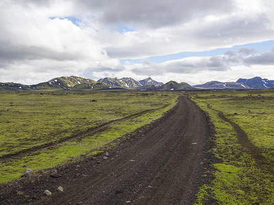 冰岛 Fjallabak 自然保护区废弃绿色景观中的土山路 F210 景观，色彩缤纷的雪覆盖着流纹山，蓝天白云