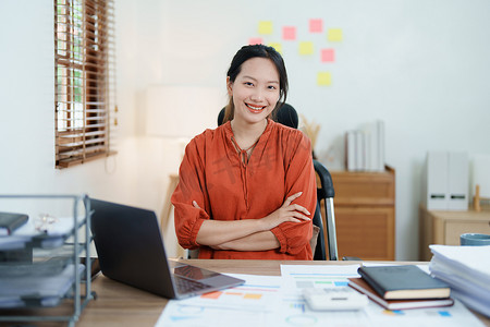 一位女企业主在工作中使用计算机和财务预算文件成功投资了她的企业，脸上露出幸福的笑脸
