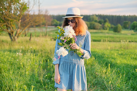 戴着牛仔裤礼帽、戴着野花花束的美丽少女