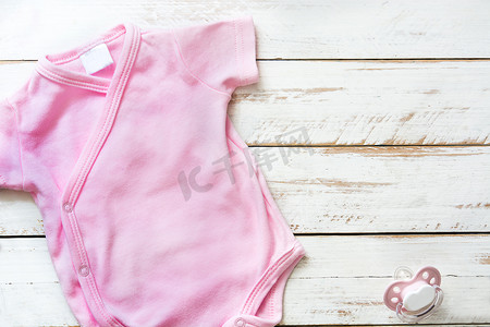 白色木制背景上的粉红色婴儿连衣婴儿。