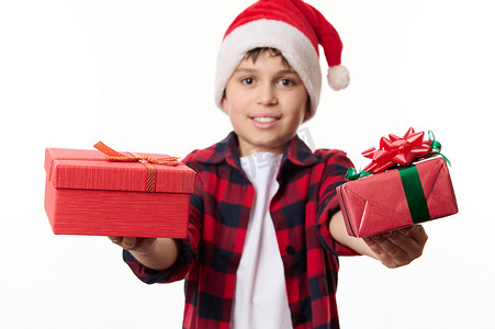 男新年摄影照片_专注于圣诞快乐或新年礼物，手上戴着圣诞帽、孤立在白色背景中的模糊的漂亮男孩手中