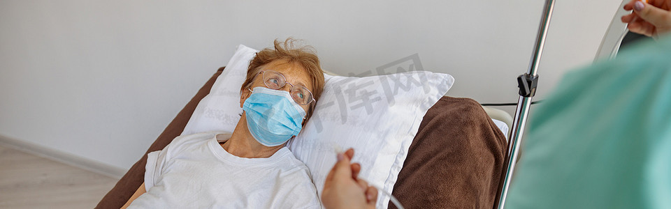 Covid 19大流行期间，护士戴着口罩给病人的手臂打点滴