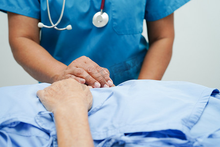 医者摄影照片_医生手牵亚洲老年女病人的手，在医院提供帮助和护理。