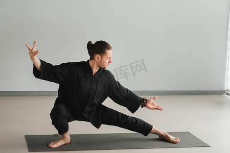 气功摄影照片_穿着黑色和服的男子在室内练习气功能量练习