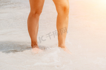 行走的女人摄影照片_海滩旅行-在沙滩上行走的女人在白色的沙滩上留下脚印。