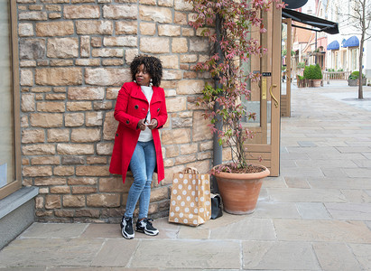 淡季摄影照片_街上站着购物袋的曲线优美的非洲裔美国女人