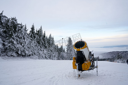 雪扇摄影照片_德国罗恩黑塞州 Wasserkuppe 滑雪胜地的黄色人造雪炮，2022 年 12 月新降雪后的雪山上
