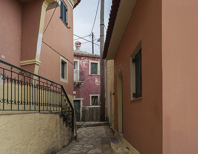 希腊科孚岛，狭窄的街道和古老的红色房屋，门面剥落，绿色门窗，复古外观