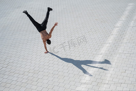 赤裸上身的男人在户外用手行走。