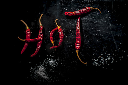 在一些红辣椒的帮助下，在黑色表面上写下“HOT”。