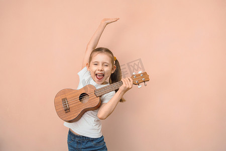 富有表现力的小学年龄白人女孩通过弹儿童吉他来学习音乐