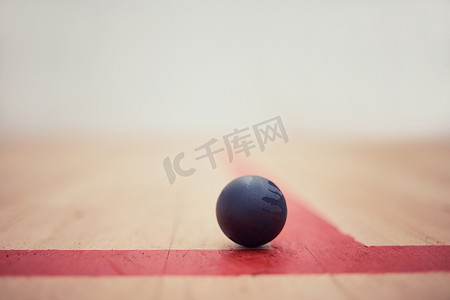 一个壁球的特写镜头在木地板上的在体育中心的空的球场上与复制空间。