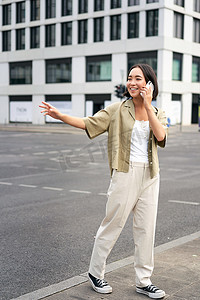 年轻女子向出租车司机挥手，打电话或用手机通话，叫车，站在街上的户外