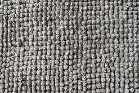 灰色的花纹背景摄影照片_由小球制成的灰色毯子的纹理。