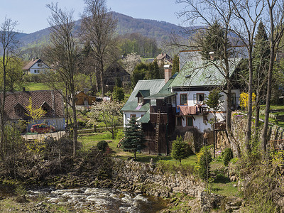 房屋山摄影照片_捷克共和国伊泽拉山 Hejnice 村 Hejnice 的景观，春天有小屋和小溪