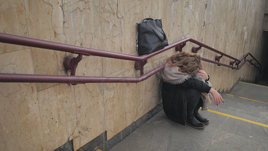 暴风哭泣摄影照片_一个小女孩在地铁楼梯旁哭泣。