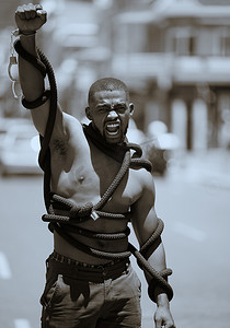 抗议、拳头和戴着绳子和手铐的人在城市抗议歧视、压迫或奴役和种族主义。