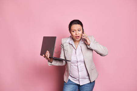 愤怒的怀孕女商人拿着笔记本电脑，在谈论手机职业时争论。