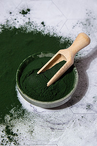 功能食品摄影照片_蓝绿藻小球藻和螺旋藻粉在碗里用木勺。