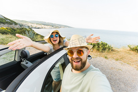 幸福美丽的情侣在度假时在路上驾驶敞篷车拍摄自拍照。