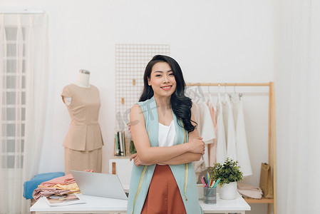 快乐的亚洲时装设计师女商人在工作室的肖像。