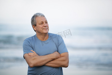 思念的摄影照片_快乐的退休男子，双臂交叉在海边