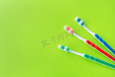 彩色牙刷摄影照片_绿色背景的彩色牙刷、牙科护理和口腔卫生的概念。