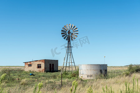 风车小屋摄影照片_废弃农场工人房屋、风车和水坝