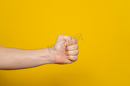 大力士的手以拳头的形式水平，隔离在黄色背景上。