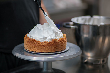 面包造型摄影照片_糕点师设计师用抹刀在馅饼皮上填充柠檬味蛋白酥皮慕斯奶酪奶油