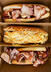 热狗摄影照片_不同口味的美式热狗，白色的桌子上放着奶酪和脆洋葱，简约风格。