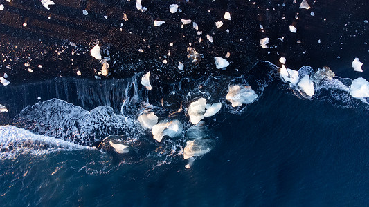 保温暖水壶摄影照片_海水中融化的北极冰，冰岛黑色火山海滩上的蓝色冰川冰和雪。