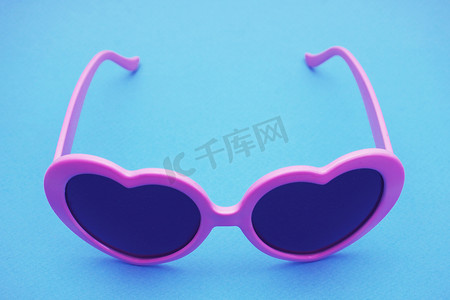 边框眼镜摄影照片_蓝色背景上的深紫色边框眼镜。