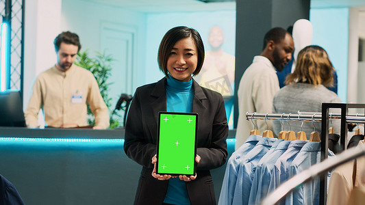 平板电脑绿幕摄影照片_亚洲商店助理在平板电脑上使用绿屏显示