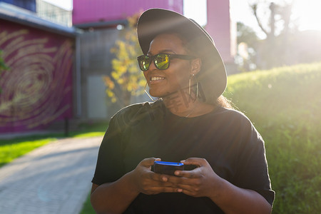 城市中快乐的非洲裔美国年轻女性浏览社交网络的特写肖像 — z 一代和城市概念
